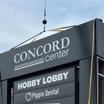 Signboard with 'Concord Center', 'Hobby Lobby', and 'Pippin Dental' logos against a blue sky.
