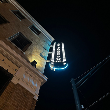 An illuminated blade sign mounted to the side of a building at night.